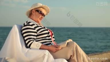 老年妇女在海边享受假期，<strong>阅读书籍</strong>